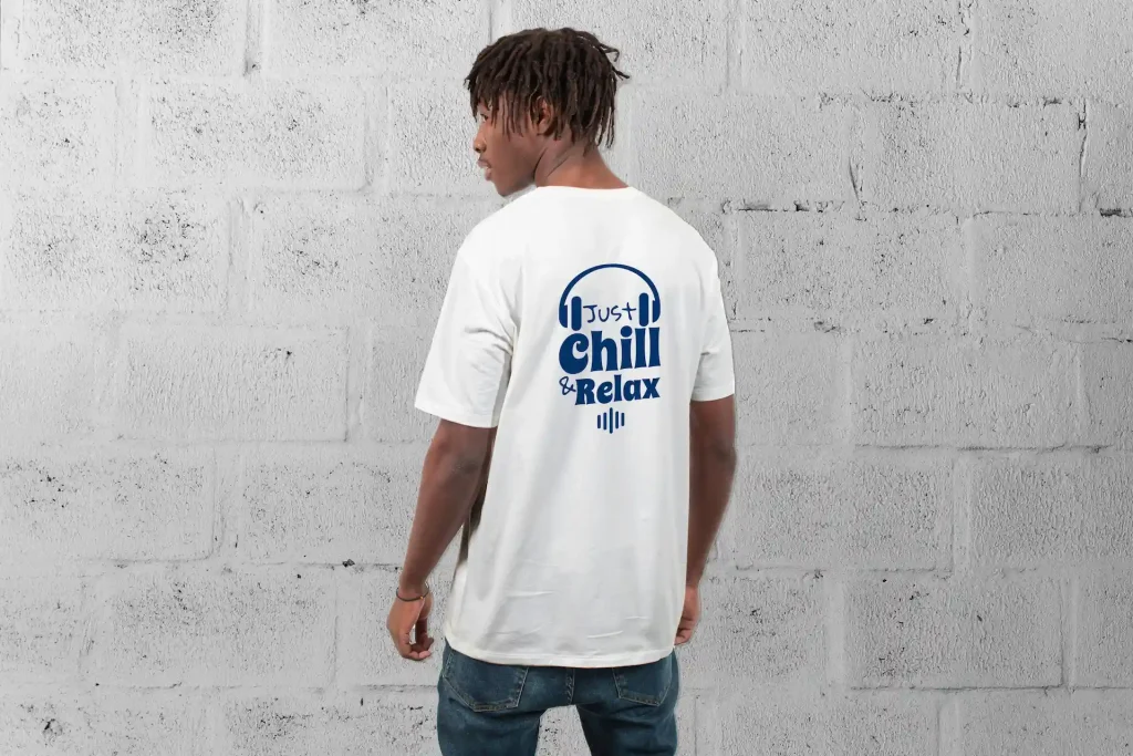 Homme de dos portant un T-shirt Blanc avec ecrit en bleu " Just Chill and Relax" de facon stylisée, avec un casque audio encadrant le "Just"