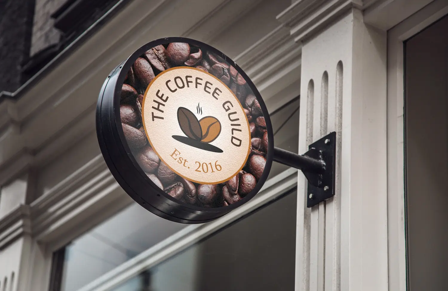Enseigne commerciale "The Coffee Guild". Le logo représente des grains de café, on peut voir de la fumée au dessus qui évoque le café chaud.